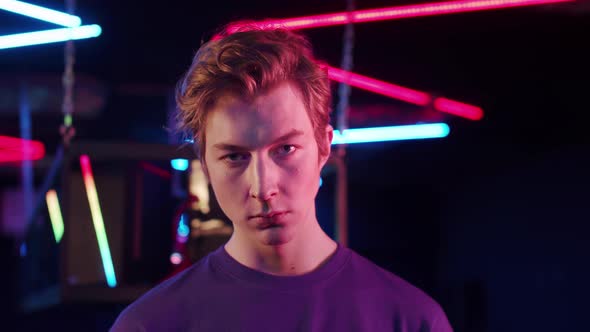 A Closeup Portrait of a Cute Teenager in a Blue Tshirt in a Computer Club in Neon Light