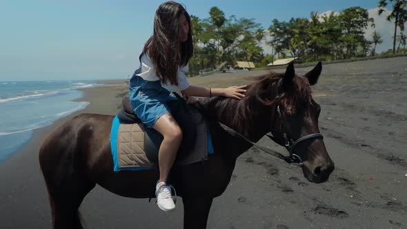 Cute Chinese Teenager Rides a Horse On The Beach In Bali