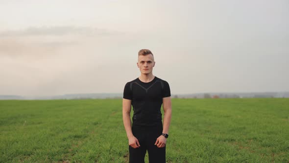 The Athlete is Standing on a Field with Green Grass