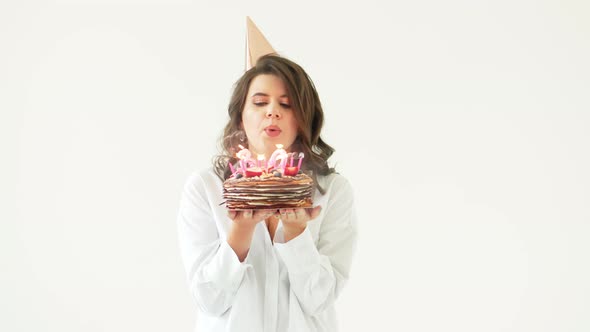 a Happy Lonely Woman with a Birthday Cake with Candles on a White Background