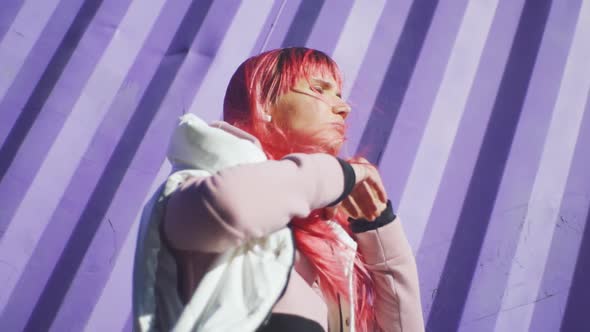 Portrait of Independent Young Woman with Pink Hair Posing on Purple Containers Background