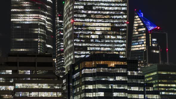 Busy office building windows at night lighting up time lapse