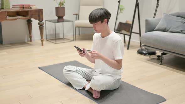 Young Asian Man Making Online Payment on Smartphone on Yoga Mat