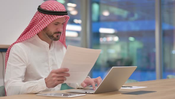 Arab Businessman Working on Laptop and Documents