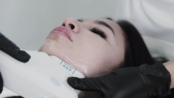 Young Brunette Woman Lying on a Couch and Having Electric Massage Procedure Under Her Chin