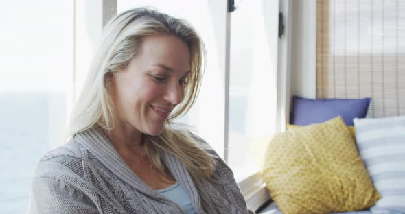 Smiling caucasian mature woman sitting and taking away hairs in sunny living room