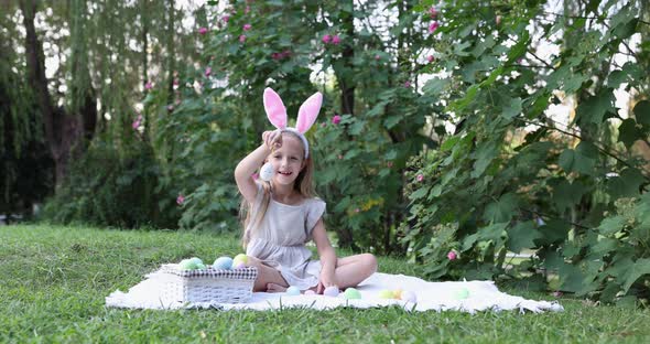 Adorable Girl Wearing Bunny Ears When Pick Up Painted Easter Egg Hunt In Garden or Park