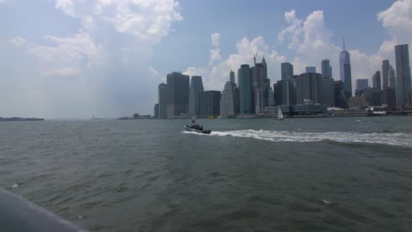 Manhattan's cityscape with boats crossing, during daytime.