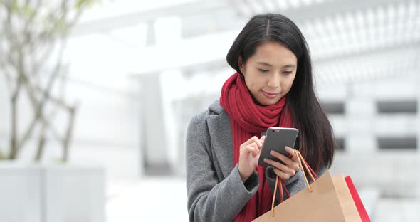 Woman use of smart phone with shopping bag