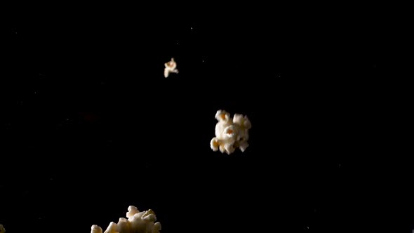 Popcorn falls in slow motion on the camera, isolated black background studio shot.