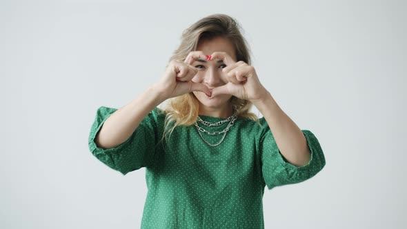 Portrait of Attractive Woman Making Beating Heart Hand Gesture and Sending Air Kisses