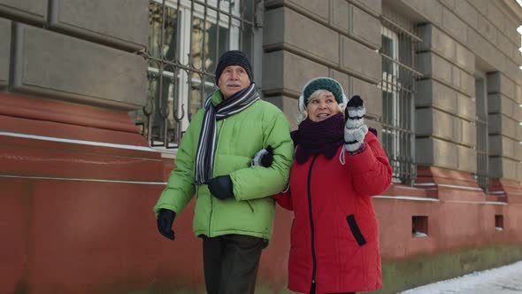 Senior Couple Man Woman Tourists Walking in Old City in Winter Talking Gesturing Holidays Vacation