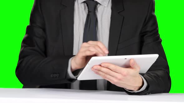 Person in Formal Suit Sitting at the Table and Uses Laptop. Green Screen