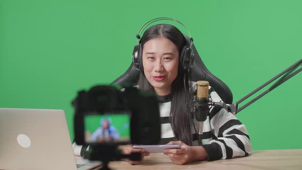 Camera Recording Video of Asian Woman With Headphone Playing Mobile Phone Game On Green Screen