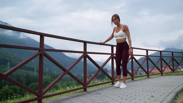 Young Sexy Woman is Doing Fitness Outdoors Swinging your Legs