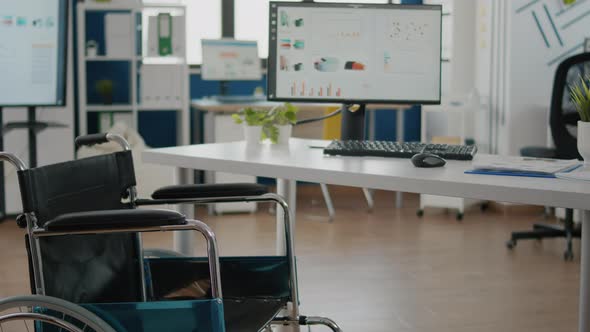 Wheelchair Parked in Empty Office Room Near Desk in Start Up Company