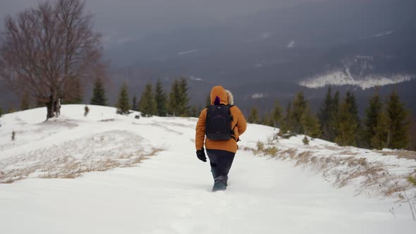 Male Tourist with a Backpack Walking in Deep Snow