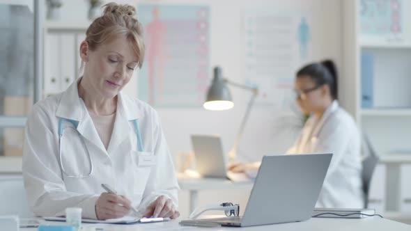 Happy Mid-Aged Female Physician Posing at Desk