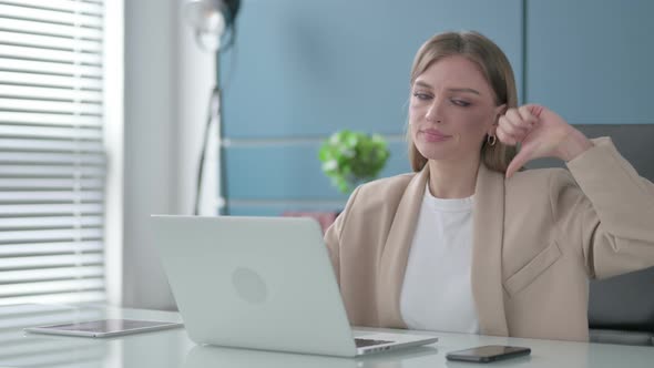 Businesswoman Showing Thumbs Down Sign While Using Laptop in Office
