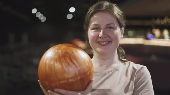 Portrait of Positive Woman with Freckles in Bowling Alley Holding Orange Ball