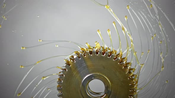 Super Slow Motion Shot of Rotating and Splashing Metal Cogwheel on Grey Background at 1000 Fps.