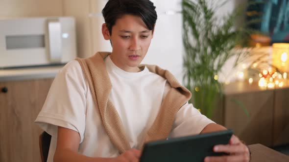 Pensive Asian man looking at tablet and to the side