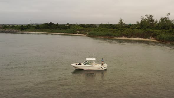 A low altitude, aerial view of an anchored fishing boat on a cloudy day. The drone camera orbits aro