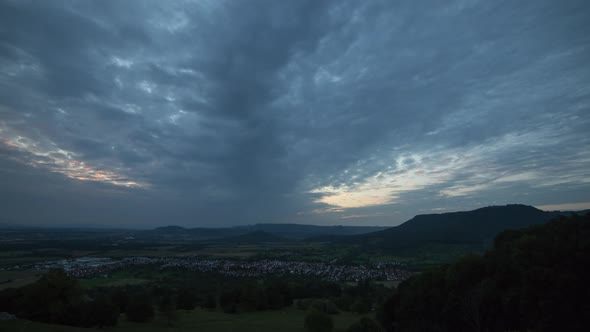 Night to day, sunrise time lapse shot at Swabian Alb in summer. With residential areas and green for