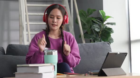 Happy young asian woman relaxing at home sit on sofa holding digital tablet enjoying