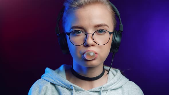 Portrait of Hipster Girl Blowing Bubble Gum Isolated at Disco Neon