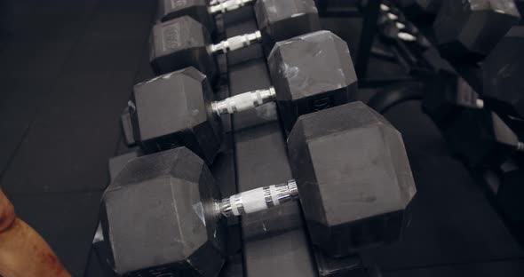 Male Hands Taking Bodybuilding Dumbbells In Gym Club. Closeup Man Hands Taking Weight