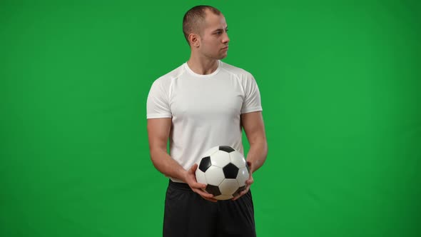 Confident Caucasian Young Man Catching Football Ball in Slow Motion on Green Screen Looking at