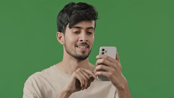 Portrait Closeup Arabian Young Man in Studio on Green Background Holding Phone Happy Smiling Guy