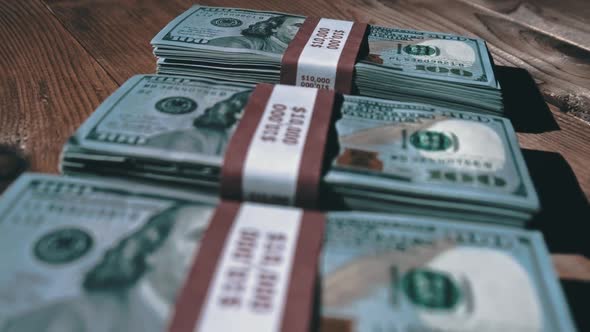 Three Stacks of 10000 American Dollars Banknotes in Bundles Lie on Wooden Table