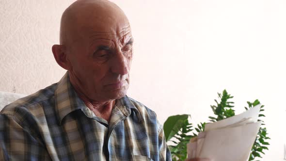 caucasian pensioner 70 years old at home looking at a stack of photos holding in his hands. elderly 