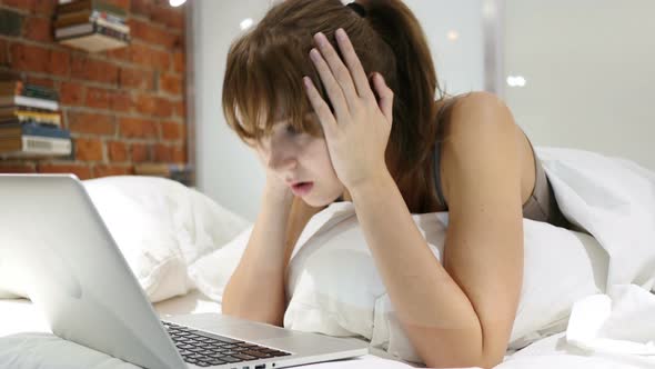 Wondering Woman in Bed in Shock by Results on Laptop