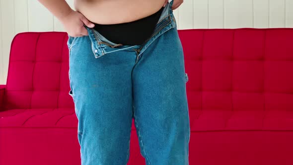 Overweight woman tries to wear pants that do not fit her size