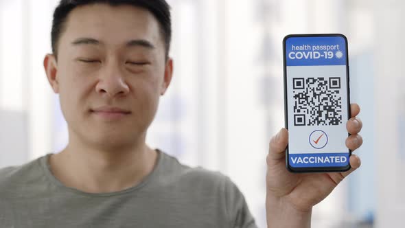 Portrait of Asian Male Person Showing Smartphone in His Hand with Mobile Application for Vaccination