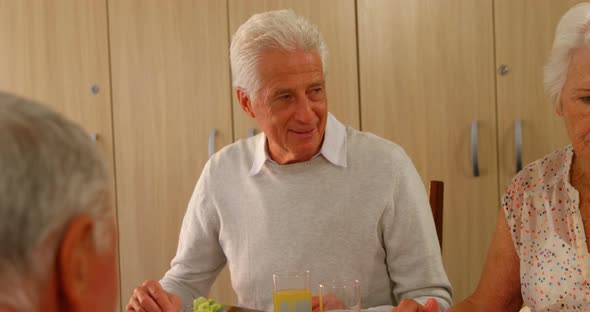 Happy senior man having meal with his friends