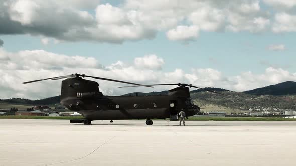 Soldier walking away from a CH-47 Chinook Helicopter as it powers up.