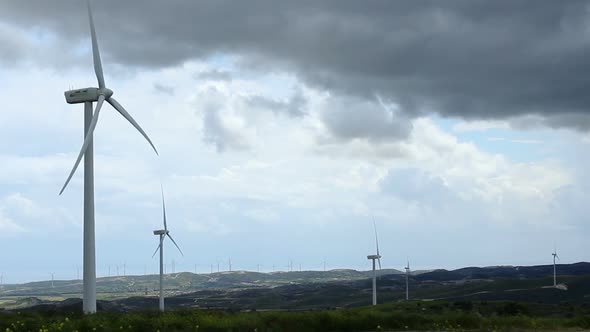 Time-Lapse of Wind Turbine Propellers Rotating in Green Field, Dark Cloudy Sky