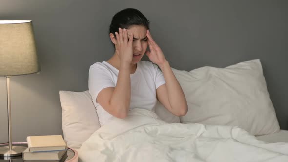 Indian Woman with Headache Sitting in Bed