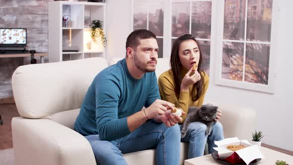 Couple Sitting on Sofa Eating Fried Chicken