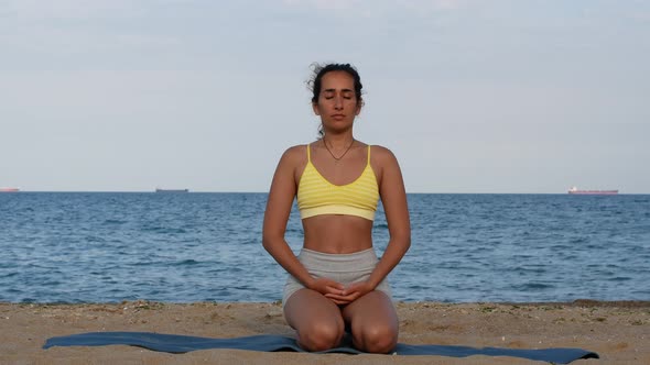 Yoga woman practices yoga and meditates in lotus position on beach sea. Healthy female