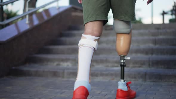 Live Camera Follows Steps of Male Amputee with Prosthesis Walking Upstairs Outdoors