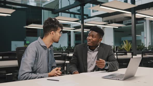 Two Diverse Men Arabian African Colleagues Coworkers Cooperate Discuss Online Project at Workplace