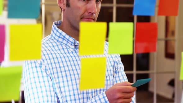 Male business executive looking at sticky notes