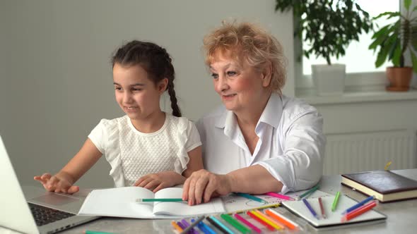 Grandmother Teaching to Granddaughter with the Help of the Computer