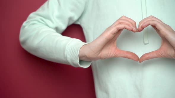 Close-up of female hands showing heart on red background