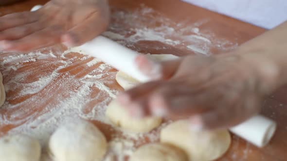 Woman Rolls the Dough with a Rolling Pin Shaping the Dough